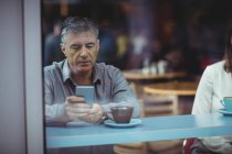 Hombre usando el teléfono móvil en la cafetería - foto de stock