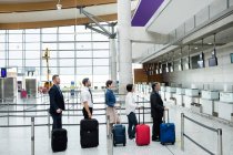 Пасажири чекають черги на стійці реєстрації з багажем всередині терміналу аеропорту — стокове фото