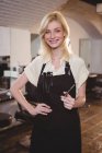 Portrait of female hairdresser standing with hand on hip at salon — Stock Photo
