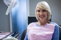 Улыбающийся пациент сидит на стоматологическом стуле в клинике — стоковое фото