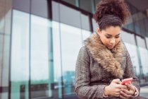 Tiefflieger: Junge Frau fährt mit Handy gegen Gebäude — Stockfoto