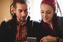 Close-up of smiling hipster couple using mobile phone at home — Stock Photo