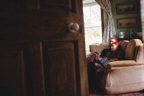 Романтична пара хіпстерів, що розслабляється на дивані, побаченому з дверного отвору вдома — стокове фото