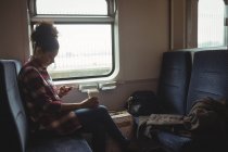 Вид сбоку на молодую женщину, пользующуюся телефоном в поезде — стоковое фото
