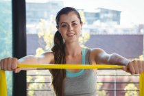 Portrait of woman holding resistance band in gym — Stock Photo