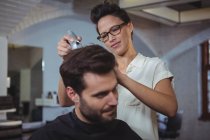 Парикмахер стрижет волосы клиента в парикмахерской — стоковое фото