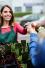 Mujer haciendo el pago con tarjeta de crédito a floristería en el centro de jardín - foto de stock