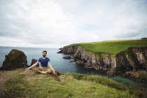 Homme effectuant le yoga sur la falaise — Photo de stock