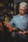 Mature shoemaker examining a boot and piece of material in workshop — Stock Photo