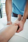 Cropped image of Physiotherapist giving physical therapy to leg of female patient in clinic — Stock Photo