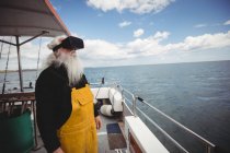 Рыбак с помощью гарнитуры виртуальной реальности на рыбацкой лодке — стоковое фото