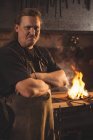 Portrait of blacksmith with arms crossed at work shop — Stock Photo