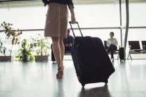 Les gens d'affaires marchant avec des bagages dans le terminal de l'aéroport — Photo de stock