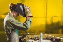 Female welder holding welding torch in workshop — Stock Photo