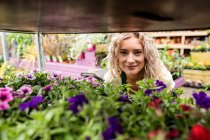 Retrato de florista femenina sonriente en el centro del jardín - foto de stock