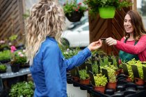 Жінка внесення оплати кредитною карткою її до флорист в садовому центрі — стокове фото