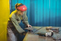 Женщина-сварщик с помощью инструмента в мастерской — стоковое фото