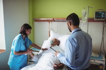 Медсестра втішає старшого пацієнта з лікарем у лікарні — стокове фото
