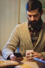 Homem usando telefone celular enquanto toma café em casa — Fotografia de Stock