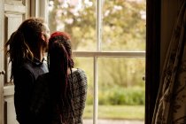 Giovane coppia che abbraccia guardando attraverso la finestra a casa — Foto stock