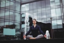 Toute la longueur de femme d'affaires faisant du yoga contre l'immeuble de bureaux — Photo de stock