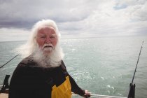 Retrato de pescador de pelo gris de pie en barco de pesca y mirando a la cámara - foto de stock