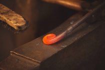 Nahaufnahme einer geschmiedeten, erhitzten Eisenstange in der Werkstatt — Stockfoto