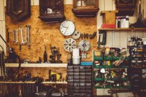 Oficina de horólogos antigos com ferramentas de reparo de relógio, equipamentos e relógios na parede — Fotografia de Stock