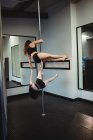 Pole dancers practicing pole dance in fitness studio — Stock Photo