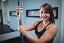 Porträt der attraktiven Pole-Tänzerin, die im Fitnessstudio die Stange hält — Stockfoto