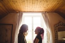 Young smiling couple standing against window at home — Stock Photo