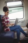 Vue latérale de la jeune femme avec ordinateur portable tout en étant assis dans le train — Photo de stock