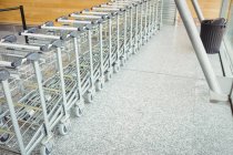 Carrinhos mantidos em uma fileira no terminal do aeroporto — Fotografia de Stock