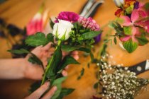 Cropped image of female florist preparing flower bouquet at her flower shop — Stock Photo
