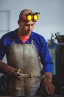 Male welder holding welding torch in workshop — Stock Photo