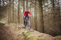 Vista frontal do ciclista de montanha andando na estrada de terra na floresta — Fotografia de Stock