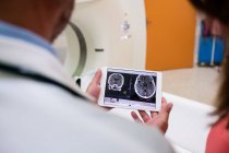 Medico che guarda la risonanza magnetica cerebrale su tablet digitale in ospedale — Foto stock