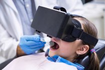 Крупный план девушки с использованием гарнитуры виртуальной реальности во время посещения стоматолога в клинике — стоковое фото