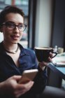 Молодая предпринимательница держит мобильный телефон в кафе — стоковое фото
