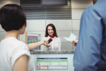 Passengers giving passport to airline check-in attendant at airport check-in counter — Stock Photo