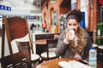Mulher bebendo café enquanto sentado no restaurante na estação ferroviária — Fotografia de Stock
