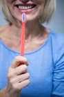 Partie médiane d'une femme souriante tenant une brosse à dents — Photo de stock