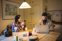Пара с помощью ноутбука и мобильного телефона дома — стоковое фото