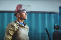 Side view of Male welder standing and looking away in workshop — Stock Photo