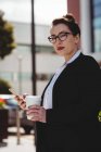 Портрет молодой предпринимательницы с мобильным телефоном и одноразовой чашкой кофе — стоковое фото