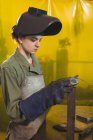 Vue latérale du soudeur femelle examinant un morceau de métal en atelier — Photo de stock