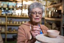 Peinture féminine de potier sur bol dans un atelier de poterie — Photo de stock
