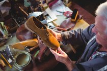 Zapatero examinando un zapato en taller - foto de stock