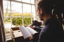 Hipster leggere romanzo da finestra a casa — Foto stock
