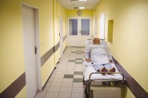 Старша жінка лежить на ношах в лікарняному коридорі — стокове фото